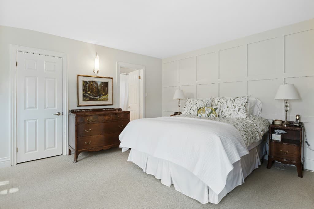 Master bedroom with panelled feature wall, premium linens, and ensuite access — Vilano Ikoyi